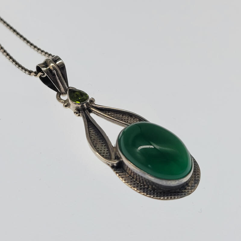 Green Agate & Peridot Necklace A large pendant made entirely in silver with a large polished green agate cabochon which is oval in shape and bezel set to the bottom of the pendant. Above what look like leaves is a teardrop shaped peridot stone hanging below the bale. The agate stone measures 13mm x 18mm Necklace measures 46cm Pendant measures 1.9cm x 5cm including the bale