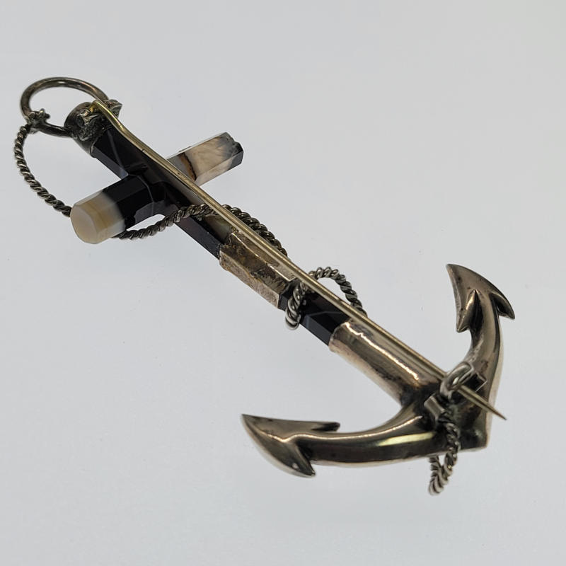 A large Victorian brooch in the form of an anchor. The shank and stock are made from striped or banded agate while the crown, fluke and balancing band are made in intricately embossed silver. Highly regarded for their metaphysical solid and protective properties, banded agates are considered to be stones of healing and release. It's believed to help one achieve peace, security, and grounding. The brooch measures 9cm x 4.3cm There are a few nibbles around one end of the agate stock.