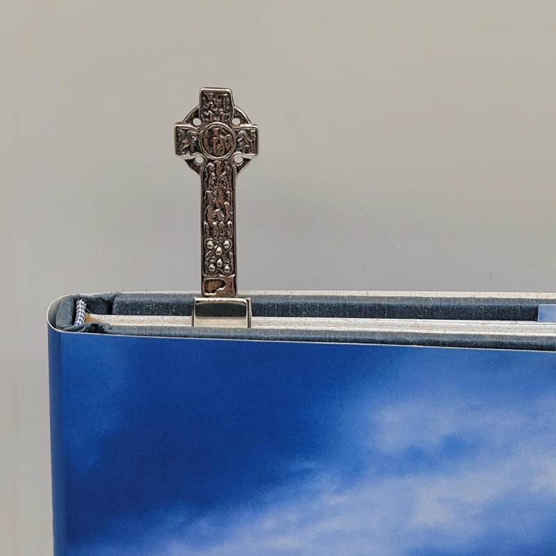 Celtic Cross Scottish Silver Bookmark A truly exquisite bookmark, crafted with utmost care and precision that embodies the rich heritage of Scotland. This remarkable piece is meticulously fashioned from 925 silver, ensuring its durability and timeless elegance.  The centrepiece of this bookmark is a splendid Celtic cross, measuring a remarkable 4cm in height. The bookmark itself, designed to securely hold your place in any literary masterpiece, extends the entire piece to a full length of 8.5cm, with a width of 1.5cm. The meticulous craftsmanship and attention to detail are evident in every aspect of this remarkable creation. The Celtic cross, with its intricate and symbolic design, serves as a testament to the deep-rooted cultural significance of Scotland. This bookmark is not only a functional accessory but also a cherished keepsake that will undoubtedly enhance your reading experience. Please note that the book is used only to illustrate the use of the bookmark and is not included.