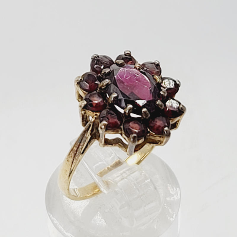 Large Vintage 9ct Oval Garnet Cluster Ring A 9ct yellow gold ring with a large oval garnet surrounded by 10 smaller round garnets, all claw set in to a flower shape. The central garnet is the largest. Hallmarked London 1979 UK Size O½ US Size 7½ Circumference 56mm